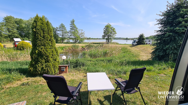 tisch und sessel vor dem campervan mit ausblick auf see masuren