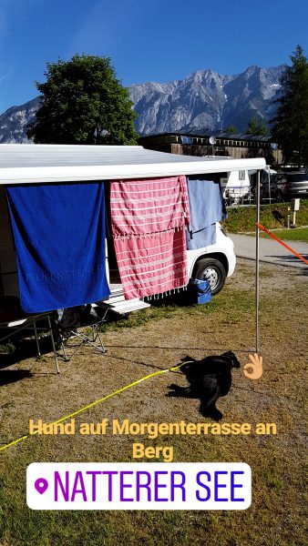 camping tipp in tirol am natterersee am berg mit sonnenschutz und schwarzem hund